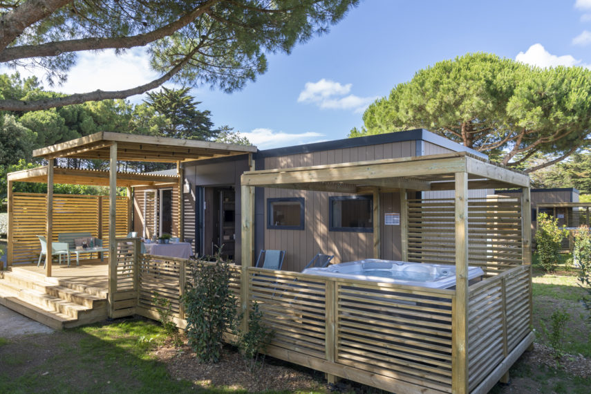 Mobil-home moderne avec terrasse et jacuzzi extérieur.